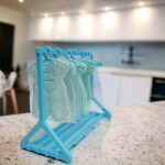 Perchero plástico celeste con 7 perchas para cookies